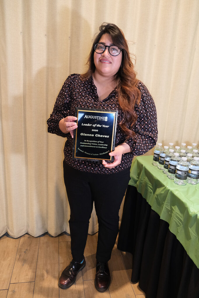 bespectacled woman holding a plaque