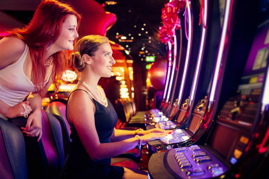 Two women playing a slot machine at a Casino.